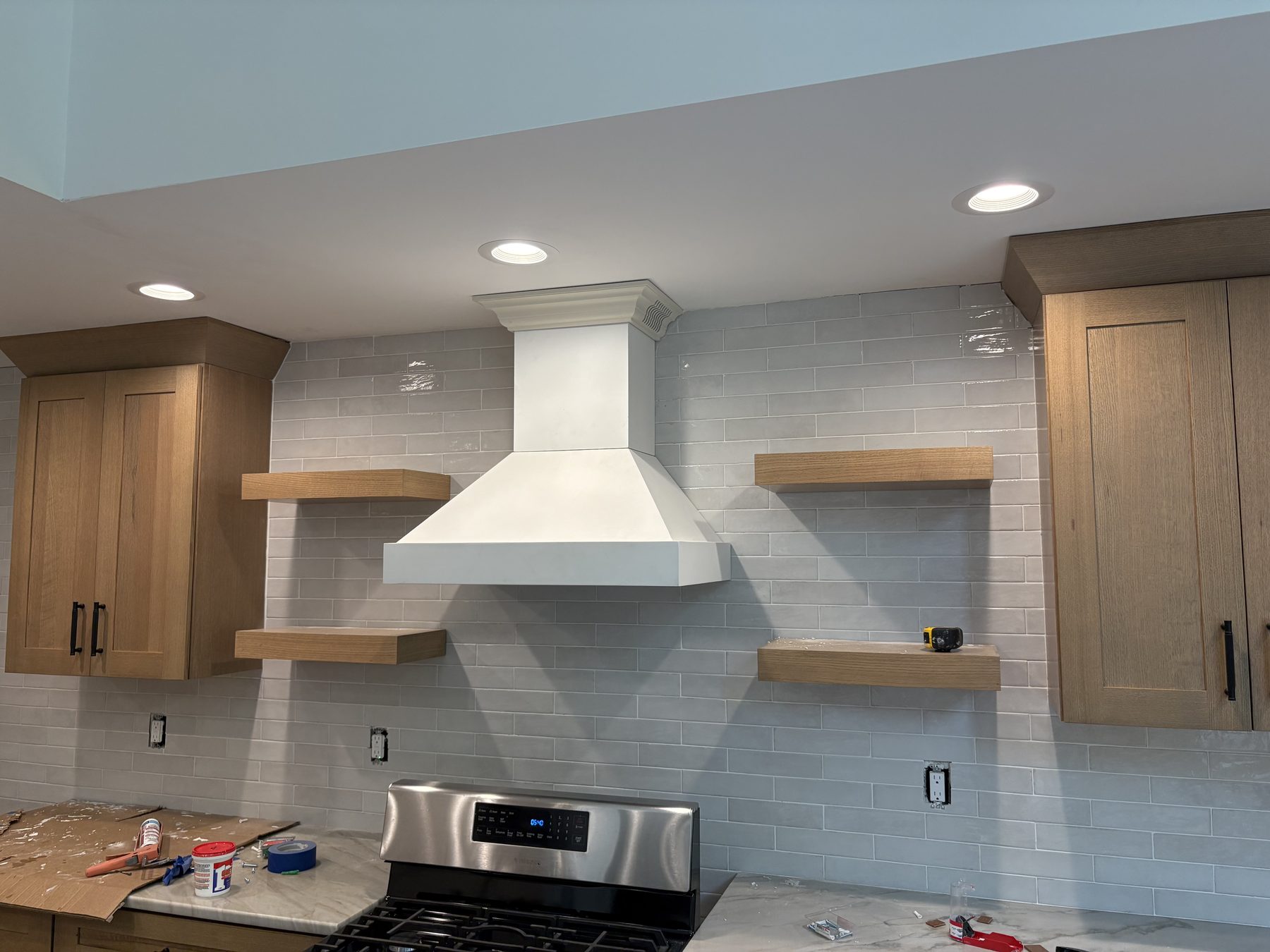 White oak kitchen with plaster range hood and subway tile